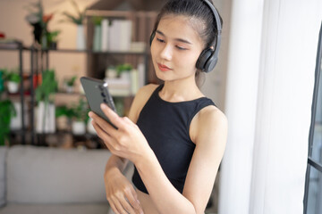 Fototapeta premium Fitness asian woman using smart phone and headphones Enjoy listening to music. Female with headphones smart phone after workout