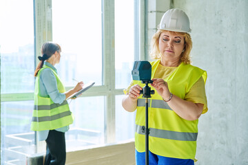 Woman industrial worker in protective vest helmet working on construction site