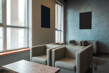 Modern lounge area with gray armchairs, large windows with blinds, and abstract wall art, cozy and stylish interior design.