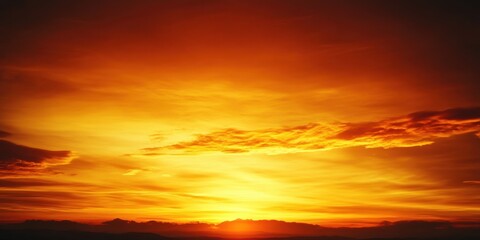 Fototapeta premium Colors of orange and yellow fill the evening sky as the sun sets beyond the mountains, creating a breathtaking view that captures the beauty of nature
