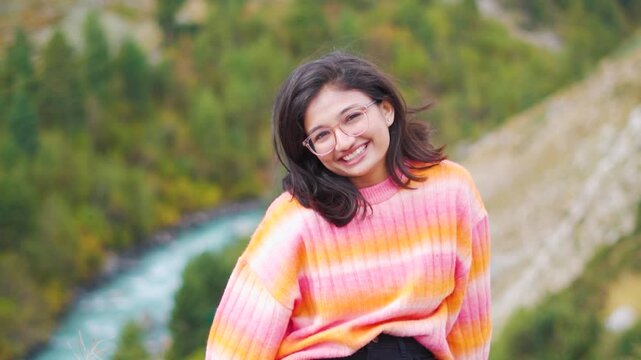 Portrait of beautiful Indian girl in mountains at Chitkul, Himachal Pradesh, India. Happy tourist enjoying vacation. New year travel goals.