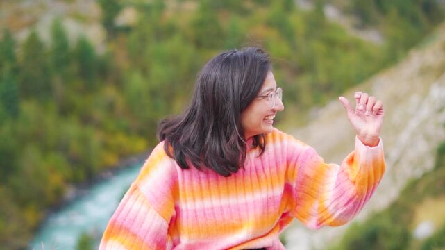 Portrait of Indian girl laughing while sitting outdoor in nature Chitkul, Himachal Pradesh, India. Tourist enjoying holidays in mountains. Travel lifestyle.