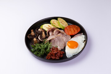 Fried egg with mash and grilled vegetables in a plate on a light background.