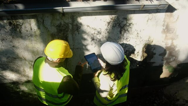 Two construction workers reviewing a tablet. Concept: construction and teamwork. Outdoor setting with shadows.