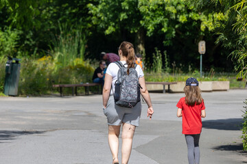 Obraz premium Rear view of mother and daughter walking in the park on a sunny day