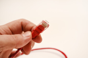 Red internet cable in hand. The RJ-45 connector.