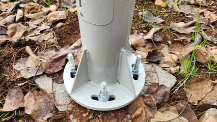 A park lighting pole is securely fastened to the concrete ground using bolts. This ensures...