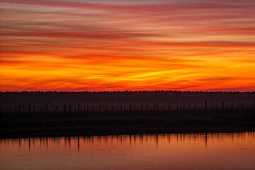 Obraz premium Golden hour sunset illuminating ocean waves crashing on sandy sea beach with colorful cloud sky