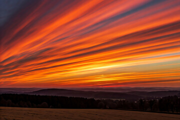 Obraz premium Golden hour sunset illuminating ocean waves crashing on sandy sea beach with colorful cloud sky