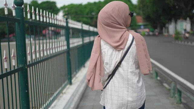 back view os asian muslim woman walking on the pedestrian walk