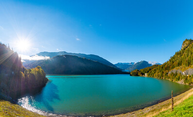 Obraz premium Sylvenstein Lake with turquoise water, autumn forest and misty mountains in Bavaria, Germany