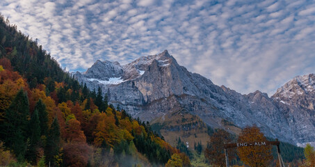 Colorful autumn landscape at Großer Ahornboden in the Karwendel Mountains, Austria – forest with fall foliage, rocky peaks and dramatic sky