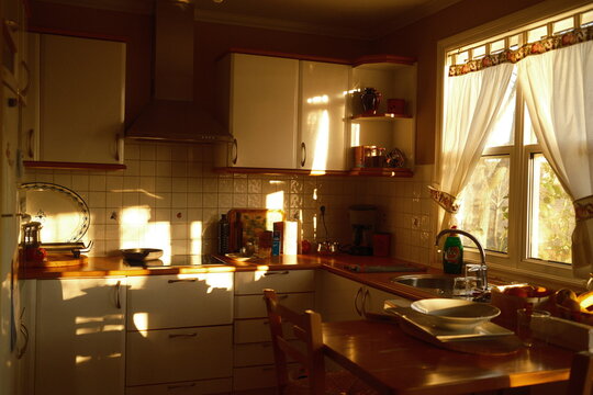 Cocina r&uacute;stica de una casa de madera con el sol del atardecer entrando por las ventanas 