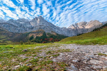 Colorful autumn landscape at Großer Ahornboden in the Karwendel Mountains, Austria – forest with fall foliage, rocky peaks and dramatic sky