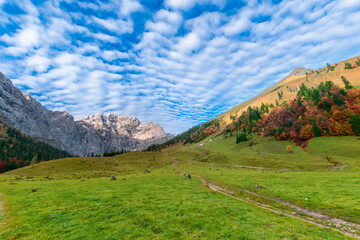 Colorful autumn landscape at Großer Ahornboden in the Karwendel Mountains, Austria – forest with fall foliage, rocky peaks and dramatic sky