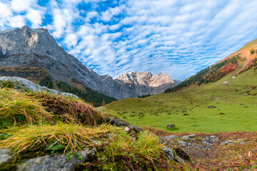 Colorful autumn landscape at Großer Ahornboden in the Karwendel Mountains, Austria – forest with fall foliage, rocky peaks and dramatic sky