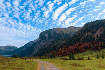 Colorful autumn landscape at Großer Ahornboden in the Karwendel Mountains, Austria – forest with fall foliage, rocky peaks and dramatic sky