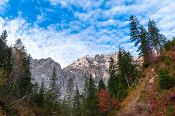 Colorful autumn landscape at Großer Ahornboden in the Karwendel Mountains, Austria – forest with fall foliage, rocky peaks and dramatic sky