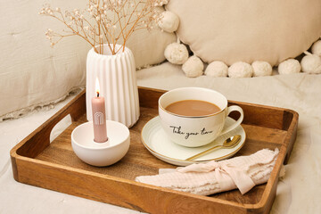 Cozy morning self-care setup with coffee cup, dried flowers and candle on wooden tray - vertical
