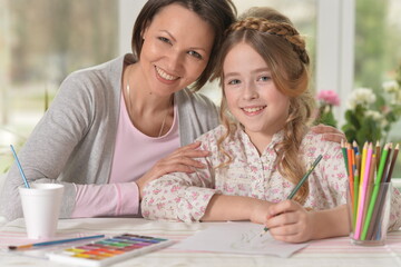 Cute mother and daughter drawing with pencils