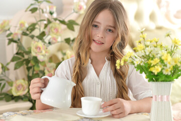 Smiling little girl holding big cup of tea