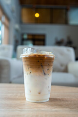 A plastic glass of iced coffee latte, upper layer is shot of espresso lower is fresh milk