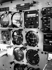 Close-up of airplane cockpit instruments and gauges in black and white, showcasing aviation technology and controls