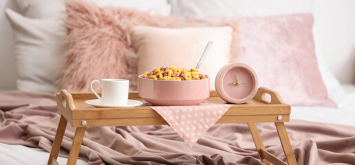 Tray with breakfast and pink alarm clock in bedroom