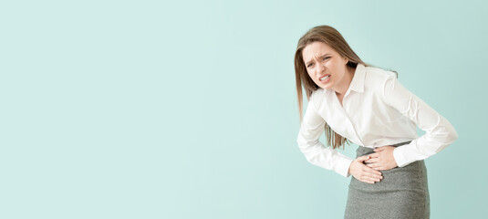 Young businesswoman suffering from abdominal pain on color background