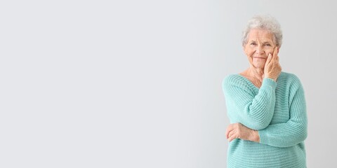 Portrait of senior woman on grey background with space for text