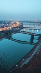 Fototapeta premium A scenic view of bridges over a river at dusk, reflecting city lights.