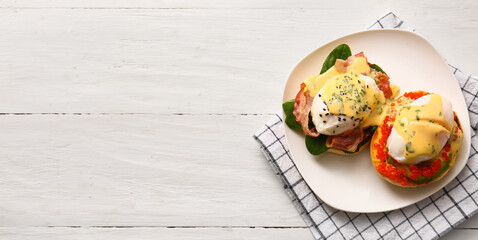 Plate with tasty eggs Benedict on white wooden table