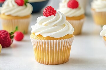 Delicious vanilla cupcake topped with creamy frosting and fresh raspberries on a light background, perfect for any celebration or dessert.