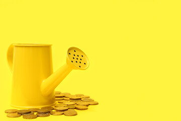 Watering can and golden coins on yellow background