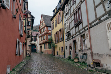 Small narrow cobblestone alleyway in Kaysersberg France on a rainy day, some half timbered homes decorated for Christmas