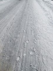 Footprint and tire track patterns on a snow-covered road in winter