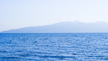 Clear blue calm sea under sunny sky, reflecting natural beauty and tranquility.