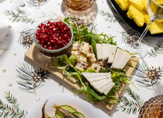 cheese platter with herbs and pomegranate seeds, cheese plate with arugula, spinach and salad. new year table, snack on the table