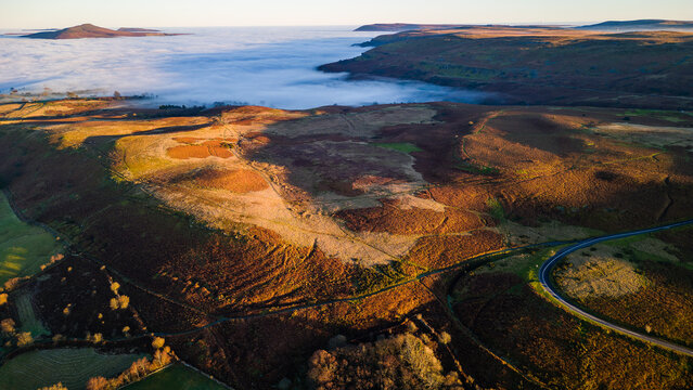Aerial shot of a fog filled valley and tall hills extending above (Crickhowell, Wales)
