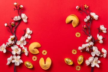 Chinese New Year composition with fortune cookies, gold coins, and cherry blossoms on a red...