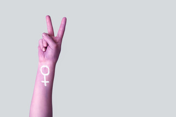 Painted hand of woman showing victory gesture on light background. Feminism concept