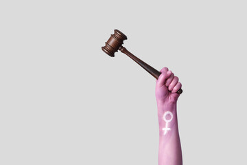Woman with painted hand holding judge's gavel on light background. Feminism concept