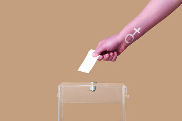 Painted hand of woman voting near ballot box on brown background. Feminism concept