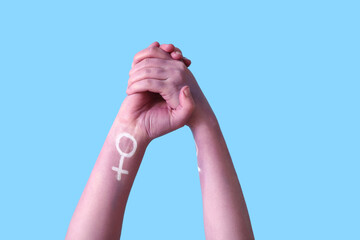 Woman holding her painted hands on blue background. Feminism concept
