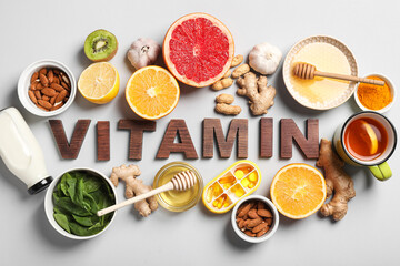 Composition with word VITAMIN made of wooden letters, pills and different healthy food on grey background. Immunity boosting concept