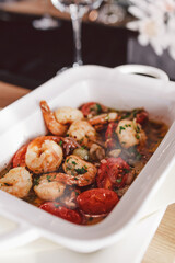 Baked shrimp with tomatoes, onions, parsley and garlic in a ceramic dish.