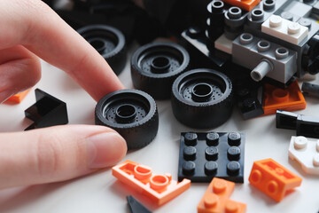 Obraz premium Tambov, Russian Federation - January 01, 2025 A young boy picking up a Lego wheel while building a Lego car. Close up.