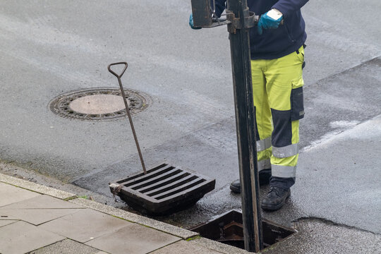 Kanalreinigung Arbeiter in Sicherheitskleidung reinigt einen Gully mit Absaugvorrichtung 