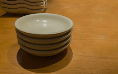 Minimalist photograph featuring empty sauce dishes arranged on a wooden table