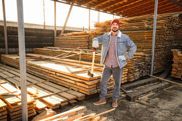 Handsome carpenter with axe at sawmill